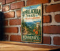 A vintage metal sign for the Appalachian Trail in Tennessee, featuring a scenic mountain landscape and trail marker.