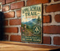 A vintage metal sign for the Appalachian Trail in Virginia, featuring a scenic mountain landscape and a trail marker.