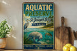 A vintage-style metal sign for the Aquatic Preserve at St. Joseph Bay in Florida, featuring illustrations of a manatee and a heron in the water.