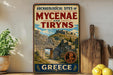 a vintage-style metal sign with the text "ARCHAEOLOGICAL SITES OF MYCENAE AND TIRYNS" and "GREECE" written on it, along with an illustration of an ancient Greek castle. The sign is displayed on a shelf next to a wooden cutting board and a potted plant.