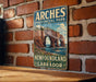 A vintage-style sign for Arches Provincial Park, New Brunswick, Labrador, and Labrador, featuring a scenic image of the park's iconic rock formations.