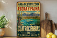 A vintage-style metal sign with a desert landscape and mountains, featuring text in Spanish that reads "Area de Protección de Flora y Fauna Cuatrocienegas Coahuila, Mexico".