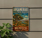a vintage-style metal sign with a desert landscape and palm trees, mounted on a wall.