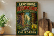 A vintage-style metal sign for the Armstong Redwoods State Natural Reserve in California, featuring a scenic illustration of the redwood forest.