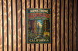A vintage metal sign for the Armstrong Redwoods State Natural Reserve in California, featuring a scenic illustration of the iconic redwood trees.