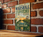 A vintage metal sign for the Marshall Loxahatchee National Wildlife Refuge in Florida, featuring an illustration of a bird and a sunset over a marsh.