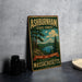 A vintage-style metal sign for Ashburnham State Forest, featuring a scenic landscape with pine trees, a lake, and mountains.