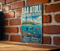 A vintage-style metal sign with the text "BAA ATOLL BIOSPHERE RESERVE MALIVES" and an illustration of a tropical island with a coral reef and marine life.