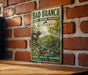 A vintage-style metal sign for Bad Branch State Nature Preserve in Kentucky, featuring a scenic landscape with a waterfall and forest.