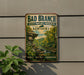 A vintage-style metal sign with the text "Bad Branch State Nature Preserve Kentucky" and a scenic illustration of a forest and a river.