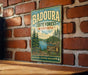 A vintage metal sign for Badoura State Forest in Minnesota, featuring a scenic illustration of pine forests and a lake.