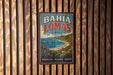 A vintage metal sign with the text "BAHIA LOMAS CHILE" displayed prominently in the center, featuring a scenic coastal landscape with mountains, palm trees, and a beach.