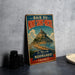 A vintage metal sign advertising the town of Mont Saint-Michel in France, featuring an illustration of the town and its surrounding landscape.