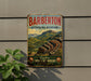 A vintage metal sign advertising the Barbarton Makhonjwa Mountains, featuring a scenic mountain landscape with a mountain peak and a river.