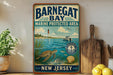 A vintage-style metal sign for Barnegat Bay, New Jersey, featuring a lighthouse, turtle, and other marine life, is displayed on a shelf next to a wooden cutting board and a potted plant.