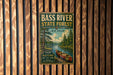 A vintage metal sign for the Bass River State Forest in New Jersey, featuring a canoe and a scenic landscape.