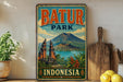 A vintage-style metal sign displaying the text "BATUR PARK INDONESIA" with an illustration of a tropical landscape featuring a mountain, temple, and water.