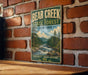 A vintage metal sign for Bear Creek State Forest in New York, featuring a scenic illustration of a forest and a river.