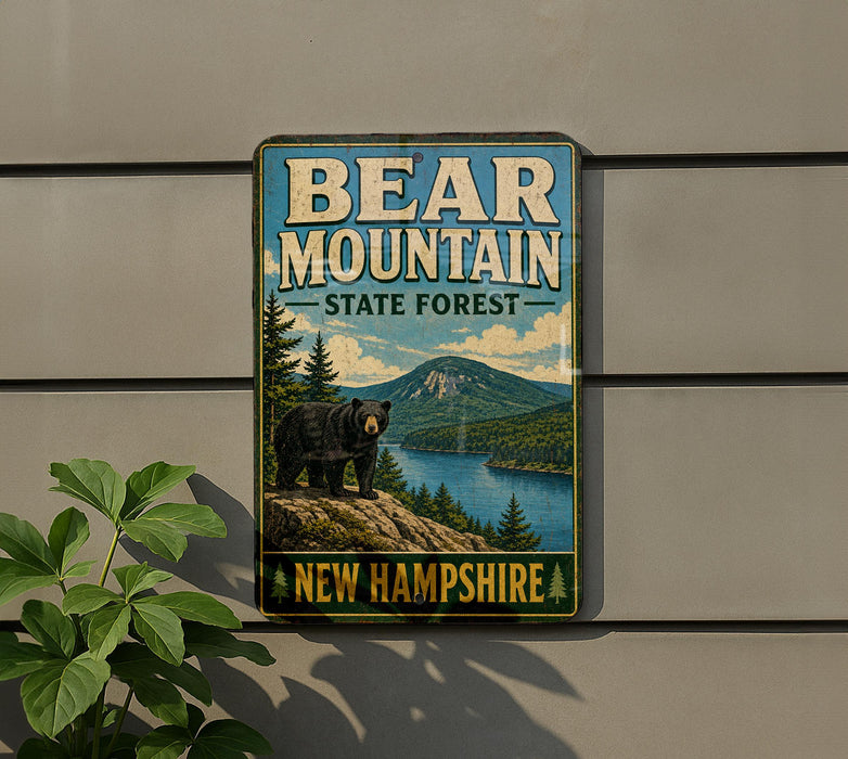 A vintage-style metal sign for Bear Mountain State Forest in New Hampshire, featuring a black bear standing on a rocky outcropping overlooking a lake surrounded by pine trees.