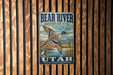 A metal sign with a bird illustration and text, mounted on a wooden wall.