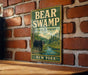 A vintage metal sign for Bear Swamp State Forest in New York, featuring a bear in a forest setting.