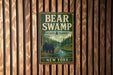 A metal sign with the text "BEAR SWAMP STATE FOREST NEW YORK" and an illustration of a bear in a forest setting.