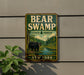 A vintage-style metal sign for Bear Swamp State Forest in New York, featuring a bear in a forest setting.