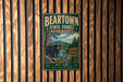 A vintage metal sign for the Beartown State Forest in Massachusetts, featuring a bear and a scenic landscape.