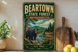 A vintage-style sign for the Beartown State Forest in Massachusetts, featuring a black bear in a forest setting.