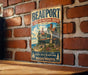 A vintage metal sign for the Beauport Sleeper-McCann House, established in 1907, is displayed on a brick wall.