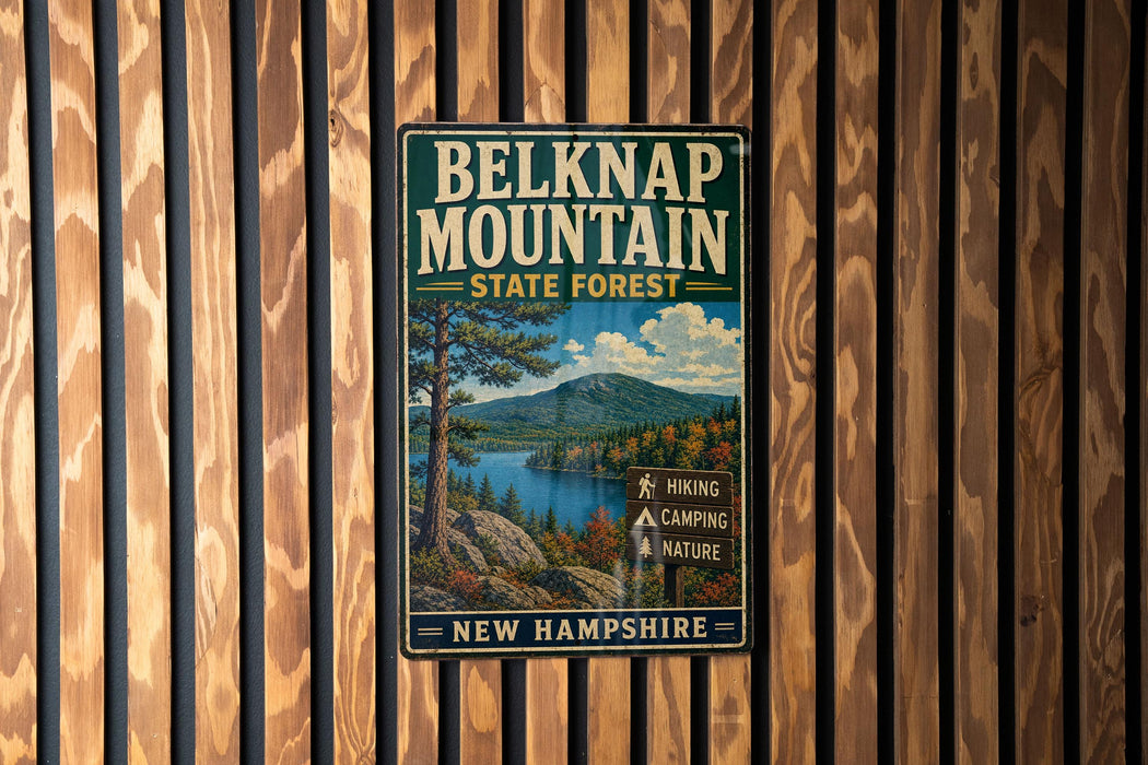 A vintage metal sign for Belknap Mountain State Forest in New Hampshire, featuring a scenic landscape with a mountain, lake, and forest.