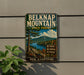 A vintage metal sign for Belknap Mountain State Forest in New Hampshire, featuring a scenic landscape with a mountain, lake, and forest.
