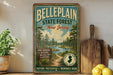A vintage-style metal sign for Belleplain State Forest in New Jersey, featuring a scenic illustration of pine trees, a river, and a path.