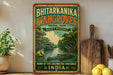 a vintage-style sign for the Bhitarkanika Mangroves, a nature reserve in Odisha, India. The sign is displayed on a wooden shelf, with a potted plant and a wooden cutting board visible in the background.
