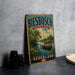 A vintage-style metal sign for Biesbach National Park in Netherlands, featuring a scenic landscape with a boat on the water.
