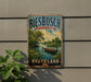 A vintage-style metal sign with the text "Biesbosch National Park - Nederland" displayed on a wall, featuring a scenic landscape with a boat on a lake.