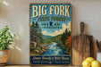 A vintage-style sign for Big Fork State Forest in Minnesota, featuring a scenic illustration of a river surrounded by pine trees and mountains.