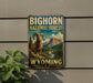 A vintage-style metal sign for the Big Horn National Forest in Wyoming, featuring a large image of a bighorn sheep against a scenic mountain landscape.