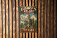 A vintage metal sign for Bishop's Palace in Texas, featuring a castle-like building and the text "Bishop's Palace A TEXAS TREASURE" in a decorative font.