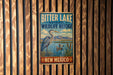 A vintage-style metal sign for the Bitter Lake National Wildlife Refuge in New Mexico, featuring an illustration of a heron and a lake with mountains in the background.