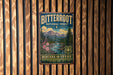 A vintage-style metal sign for the Bitterroot National Forest, featuring a mountain landscape with pine trees and a river.
