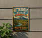 A vintage metal sign for Bitterroot Valley Heritage Landscape, featuring a scenic mountain landscape with a river and pine trees.