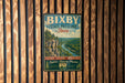 A vintage metal sign for Bixby State Preserve, Iowa, featuring a scenic landscape with a river and mountains.