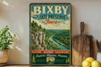 A vintage-style sign for Bixby State Preserve, Iowa, featuring a scenic landscape with a river and mountains.