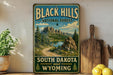 A vintage-style sign for the Black Hills National Forest, featuring a scenic mountain landscape with a lake and pine trees.