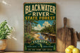 A vintage-style sign for Blackwater River State Forest in Florida, featuring a scenic image of the river surrounded by pine trees and natural beauty.