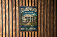 A vintage-style metal sign for the Blandwood Mansion in Greensboro, North Carolina, featuring a large illustration of the mansion surrounded by trees and a well-manicured lawn.