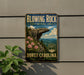 A vintage-style metal sign for Blowing Rock State Natural Area in North Carolina, featuring a scenic mountain landscape with a cliff and pink flowers.