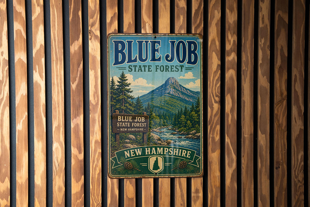 A vintage metal sign for the Blue Job State Forest in New Hampshire, featuring a mountain landscape and pine trees.
