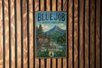 A vintage metal sign for the Blue Job State Forest in New Hampshire, featuring a mountain landscape and pine trees.